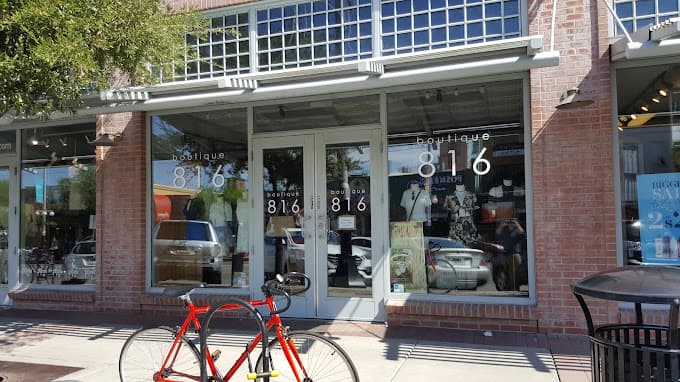 Storefront of Boutique 816. Tree to the front left, and a bike rack holding a bike up. Trashcan to the right.